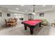 Wide angle view of the basement's game area, with a red pool table, dining set, and green sofa at 6040 Boulder Bluff Dr, Cumming, GA 30040