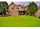 Beautiful two story brick home with stone accents, dormers, manicured landscaping, and a lush green lawn at 6040 Boulder Bluff Dr, Cumming, GA 30040