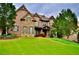 Beautiful two story brick home with stone accents, dormers, manicured landscaping, and a lush green lawn at 6040 Boulder Bluff Dr, Cumming, GA 30040