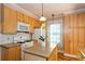 Open kitchen view featuring light wood cabinets, island, gas range, microwave, and natural light at 746 United Se Ave, Atlanta, GA 30312