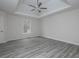 Spacious bedroom with a tray ceiling, ceiling fan, light gray wood floors, and a window at 6334 Milo Dr, Austell, GA 30168