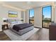 Modern bedroom features hardwood floors, a gray tufted headboard and large windows with city views at 2870 Pharr Court South Nw # 1202, Atlanta, GA 30305