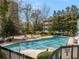 Community pool surrounded by mature trees, lounge chairs, and a seating area at 2870 Pharr Court South Nw # 1202, Atlanta, GA 30305