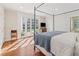 Bright main bedroom with a four-poster bed, hardwood floors, and French doors leading to a patio at 890 W Wesley Nw Rd, Atlanta, GA 30327