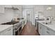 Extended view of the kitchen with stainless steel appliances, cooktop, island, and white cabinets at 3185 Casteel Ne Rd, Marietta, GA 30062
