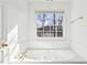 Bright bathroom featuring a large jetted tub with gold fixtures and a view from the window at 3242 Monarch Pine Nw Dr, Peachtree Corners, GA 30071