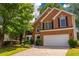 Charming two-story brick home featuring a well-manicured lawn, mature trees, and a two-car garage at 3242 Monarch Pine Nw Dr, Peachtree Corners, GA 30071