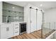 Modern bar area with shelving, gray tiled backsplash, mini fridge and sliding barn door at 7410 Fields Dr, Cumming, GA 30041