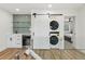 Modern laundry area with gray tiled backsplash, mini fridge, and sliding barn door at 7410 Fields Dr, Cumming, GA 30041