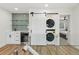 A modern laundry area offers a stacked washer and dryer concealed behind a barn door and a convenient bar sink at 7410 Fields Dr, Cumming, GA 30041