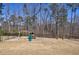 Backyard of home with playhouse and playground set in a fenced in yard with forest beyond the property line at 1775 Rockwater Rd, Marietta, GA 30066