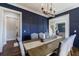 Elegant dining room features navy accent wall and a modern chandelier lighting the wood table at 1775 Rockwater Rd, Marietta, GA 30066