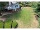 Large backyard with lush green lawn, mature trees, and a charming cottage-style home with deck at 59 Woodlawn Dr, Marietta, GA 30067