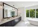 Luxurious primary bathroom with dual sinks, soaking tub, and large window with wooded views at 159 E Wesley Ne Rd, Atlanta, GA 30305