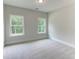 This bedroom features neutral carpeting, light grey walls, and two windows with views of trees at 3292 Mill Forest Sw Dr, Conyers, GA 30094