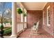 Inviting front porch featuring brick flooring, comfortable rocking chairs, and hanging ferns at 3821 Teesdale Ct, Atlanta, GA 30350