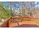 An outdoor deck featuring wood-stained railings with a view of the wooded backyard and mature trees at 713 Shore Ln, Lithonia, GA 30058
