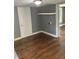 Neutral living room with wooden floors, white door, and grey accent wall at 5160 Avery St, Covington, GA 30014