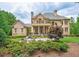 Expansive backyard featuring a manicured lawn, mature trees, a stone patio, and an inviting balcony above at 3299 Carmichael Pl, Duluth, GA 30097