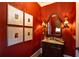 Stylish powder room with red walls, decorative sconces, framed art, and a carved wood vanity at 3299 Carmichael Pl, Duluth, GA 30097