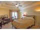 Cozy bedroom featuring a tray ceiling, a ceiling fan, a window with curtains, and a bed with pillows at 3299 Carmichael Pl, Duluth, GA 30097