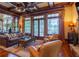 Warm living room with coffered ceilings, large windows with curtains, a leather sofa, and a stone fireplace at 3299 Carmichael Pl, Duluth, GA 30097