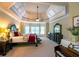 Luxurious bedroom featuring a tray ceiling, sitting area, and ample natural light from large windows at 3299 Carmichael Pl, Duluth, GA 30097