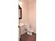 Compact half bathroom with pedestal sink, toilet, and stylish mirror at 3356 Sardis Bend Dr, Buford, GA 30519