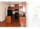View of kitchen with dark wood cabinets, black appliances, island and hardwood floors at 3356 Sardis Bend Dr, Buford, GA 30519
