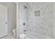 Stylish bathroom featuring marble tile and a bathtub with a shower head and a built in decorative niche at 1944 Lakewood Se Ter, Atlanta, GA 30315