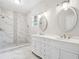 Bathroom with double vanity, oval mirrors, tiled walk-in shower with stone floor at 1944 Lakewood Se Ter, Atlanta, GA 30315