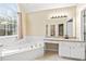 Bright bathroom featuring a soaking tub beneath a large window and a vanity with granite countertops at 1811 Lake Cove Sw Dr, Atlanta, GA 30331