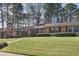 Charming ranch-style home featuring a stone chimney and well-manicured lawn with mature landscaping and an American flag at 3346 Stonecrest Ct, Atlanta, GA 30341