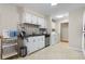 Well-lit kitchen area with white cabinets, stainless steel dishwasher, and convenient laundry access at 3346 Stonecrest Ct, Atlanta, GA 30341