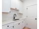 Well-appointed laundry room with white cabinetry and a black sink and door hardware at 3395 Lee St, East Point, GA 30344