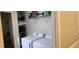 Convenient laundry room with washer, dryer, storage shelves, and adjacent staircase at 75 Doves Nest, Covington, GA 30016