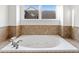Soaking tub with tile surround sits beneath a window with view of the home's exterior at 232 Hunt Ne St, Marietta, GA 30060