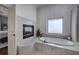 Bathroom featuring jacuzzi tub, fireplace, tile surround and access to the main bedroom at 2160 Kensington Gates Nw Dr, Kennesaw, GA 30152