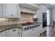 A gourmet kitchen featuring granite countertops, stainless steel appliances, a range hood, and custom white cabinets at 2160 Kensington Gates Nw Dr, Kennesaw, GA 30152