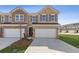 Beautiful brick two-story townhouse featuring a two-car garage and a well-manicured front yard at 935 Elwood St, Dacula, GA 30019