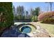 Inviting backyard features a stone hot tub next to the in-ground pool, surrounded by lush landscaping and mature trees at 1364 Manget Way, Dunwoody, GA 30338