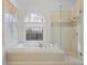 Bright bathroom featuring a soaking tub, separate glass shower, and large arched window at 549 Trailwood Sw Ln, Marietta, GA 30064