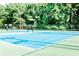 A well-maintained tennis court with blue and green surfaces, surrounded by tall trees at 549 Trailwood Sw Ln, Marietta, GA 30064