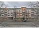 A multi-story building featuring balconies, visible through bare trees on a cloudy day, with street in front at 230 E Ponce De Leon Ave # 327, Decatur, GA 30030