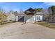Front exterior with an ample driveway, covered entry, and a glimpse of the fenced yard at 695 Old Peachtree Rd, Lawrenceville, GA 30043