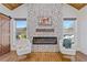 Cozy living area featuring a stone fireplace flanked by sun-drenched windows and hardwood floors at 695 Old Peachtree Rd, Lawrenceville, GA 30043