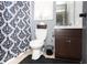 A traditional-style bathroom featuring a toilet, sink with dark cabinet, framed mirror, and shower with blue patterned curtains at 710 Josh Ln, Lawrenceville, GA 30045