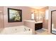 A well-lit bathroom features a tub, framed artwork, and a vanity with a dark cabinet and a white countertop at 710 Josh Ln, Lawrenceville, GA 30045