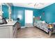 A cozy bedroom with blue walls features a bed, dresser, mirror, and wood-look flooring at 710 Josh Ln, Lawrenceville, GA 30045