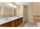 Bathroom featuring double sink vanity, large mirror, and tile accents on the tub and surrounding walls at 7438 Chilton Ln, Riverdale, GA 30296